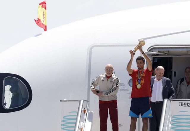 Spain's captain Rodri holds up their trophy next to Spain's coach Luis de la Fuente (L) as they disembark their plane upon their arrival from the US after winning the 2026 World Cup, in Madrid Barajas' airport, on July 20, 2026. Spain's World Cup winners come back home to a heroes' welcome in Madrid, where a million fans are expected to greet them after a night of raucous celebrations across the country. (Photo by Oscar DEL POZO / AFP)