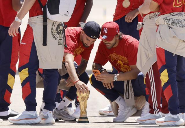 Spain's midfielder #15 Alex Baena touches their trophy on the tarmac upon the team's arrival from the US after winning the 2026 World Cup, in Madrid Barajas' airport, on July 20, 2026. Spain's World Cup winners come back home to a heroes' welcome in Madrid, where a million fans are expected to greet them after a night of raucous celebrations across the country. (Photo by Oscar DEL POZO / AFP)