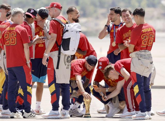 Spain's players look at their trophy on the tarmac upon their arrival from the US after winning the 2026 World Cup, in Madrid Barajas' airport, on July 20, 2026. Spain's World Cup winners come back home to a heroes' welcome in Madrid, where a million fans are expected to greet them after a night of raucous celebrations across the country. (Photo by Oscar DEL POZO / AFP)