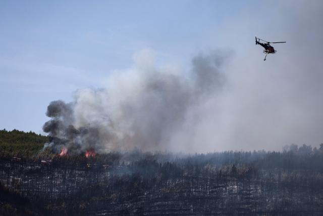 An Airbus Helicopters H125 helicopter flies after dropping water on a burning forest during a wildfire in Taradeau, in Var department of Provence-Alpes-Côte d'Azur region, southeastern France on July 20, 2026. The intense fire that broke out on July 19 afternoon in the Var, was showing signs of improvement by evening, but had affected around ten houses and around fifty houses were affected. (Photo by Thibaud MORITZ / AFP)