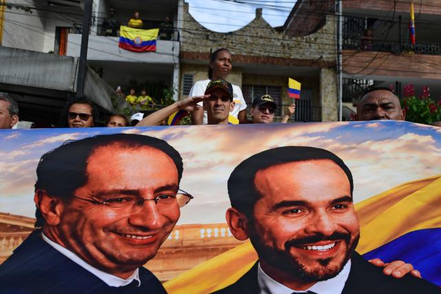Supporters of Colombia's president-elect Abelardo de la Espriella hold a banner depicting him and vice-president-elect Jose Manuel Restrepo during a military parade commemorating Colombia's Independence Day in Medellin, Colombia, on July 20, 2026. De la Espriella attended teh event. (Photo by Jaime SALDARRIAGA / AFP)