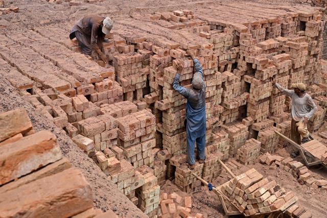 Men work at a brick kiln in Sheikhupura, in Pakistan’s Punjab province on July 20, 2026. (Photo by Arif ALI / AFP)