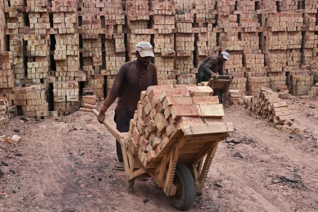 A worker pushes a wheelbarrow at a brick kiln in Sheikhupura, in Pakistan’s Punjab province on July 20, 2026. (Photo by Arif ALI / AFP)