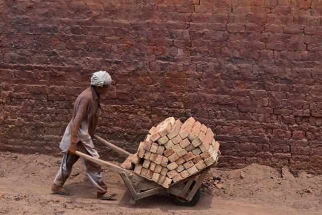 A worker pushes a wheelbarrow at a brick kiln in Sheikhupura, in Pakistan’s Punjab province on July 20, 2026. (Photo by Arif ALI / AFP)