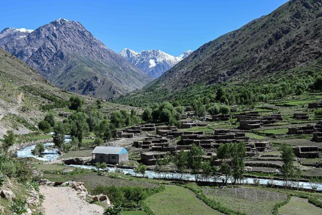 (FILES) This photograph taken on June 8, 2026 shows a river flowing past houses at the Eshtiwi village in Afghanistan's Parun district. More than 100 people are missing and nine bodies recovered after a major flood hit the capital of Afghanistan's Nuristan province on July 20. (Photo by Wakil KOHSAR / AFP)