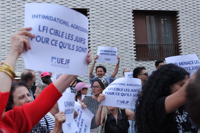 Demonstators hold placards that read " as they take part in a concert-rally called by the UEJF association (Union of the Jewish Students of France) near the headquarters of French left wing party La France Insoumise (LFI) to protest against an interruption of a DJ's concert the previous weekend, in Paris on July 20, 2026. On July 20, 2026, La France Insoumise came under fire from the rest of the political class after a concert by DJ Barbara Butch was interrupted in Grenoble on July 18, 2026, due to a protest by pro-Palestinian activists, as the date had been the subject of a boycott call since May, notably from the Grenoble branch of La France Insoumise. (Photo by Xavier GALIANA / AFP)