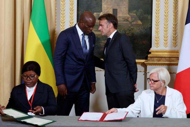 Gabon's President Brice Oligui Nguema (2ndL) and France's President Emmanuel Macron (R) talk as France's Defence Minister Catherine Vautrin and Gabon's Defence Minister Brigitte Onkanowa (L) sign documents related to the sale of the “General de Gaulle” camp on the sidelines of the state visit of Gabon's President at the Elysee Palace in Paris on July 20, 2026. (Photo by Ludovic MARIN / POOL / AFP)