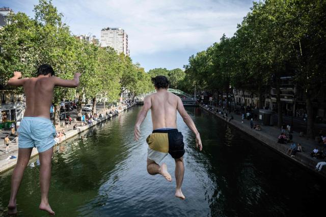 Two men dive from a bridge into the Canal Saint-Martin during summer in Paris, on July 20, 2026. (Photo by JULIEN DE ROSA / AFP)