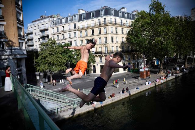 Two men dive from a bridge into the Canal Saint-Martin during summer in Paris on July 20, 2026. (Photo by JULIEN DE ROSA / AFP)