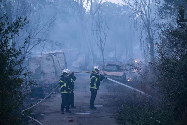 Firefighters extinguish a fire which destroyed nearly 10 hectares of vegetation near a "shantytown" in Nantes, western France, on July 20, 2026. According to local media, the fire whose plumes of black smoke were visible from many neighbourhoods in Nantes broke out near a travellers’ camp. The fire service, which mobilised nearly 150 personnel, reported that the fire had "spread significantly to makeshift dwellings". (Photo by Sebastien Salom-Gomis / AFP)
