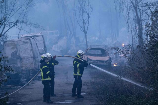 Firefighters extinguish a fire which destroyed nearly 10 hectares of vegetation near a "shantytown" in Nantes, western France, on July 20, 2026. According to local media, the fire whose plumes of black smoke were visible from many neighbourhoods in Nantes broke out near a travellers’ camp. The fire service, which mobilised nearly 150 personnel, reported that the fire had "spread significantly to makeshift dwellings". (Photo by Sebastien Salom-Gomis / AFP)