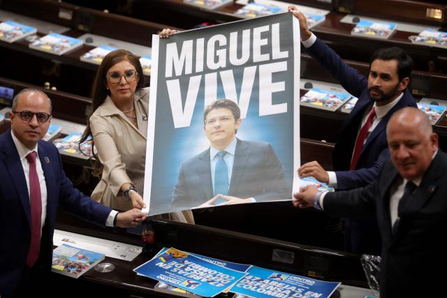 Lawmakers hold a poster reading "Miguel Lives" depicting slain Colombian senator and presidential hopeful Miguel Uribe during the installation of the ordinary sessions of Congress in Bogota on July 20, 2026. (Photo by ESTEBAN VEGA LA-ROTTA / AFP)