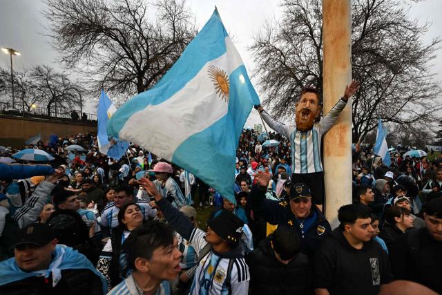 A fan wearing a mask depicting Argentina's forward Lionel Messi waves an Argentine flag close to the Argentine Football Association (AFA) training camp in Ezeiza, Buenos Aires Province, on July 20, 2026, while waiting for the arrival of Argentina's national football team from the United States following its defeat in the 2026 FIFA World Cup final. (Photo by Luis ROBAYO / AFP)
