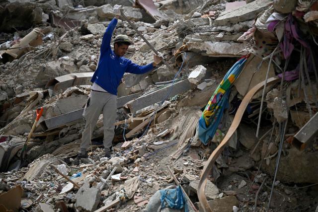 A man stands atop the rubble of a collapsed building searching through the debris in Caraballeda, Venezuela, on July 20, 2026, following the June 24 earthquakes. (Photo by Federico PARRA / AFP)
