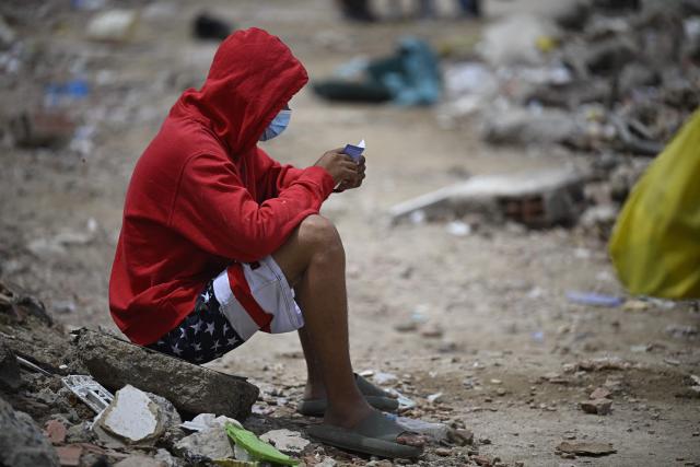 A man wearing shorts patterned with the US flag sits amid debris and rubble in Caraballeda, Venezuela, on July 20, 2026, following the June 24 earthquakes. (Photo by Federico PARRA / AFP)