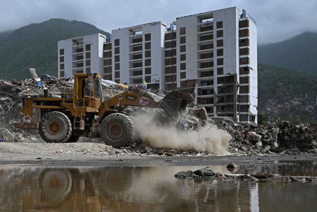 A skid-steer loader operates in front of the collapsed remains of a residential building that collapsed following the June 24, 2026 earthquakes, in Caraballeda, Venezuela, on July 20, 2026. (Photo by Federico PARRA / AFP)