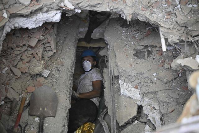 A person searches for victims' bodies beneath the rubble of a residential building that collapsed following the June 24 earthquakes, in Caraballeda, Venezuela, on July 20, 2026. (Photo by Federico PARRA / AFP)