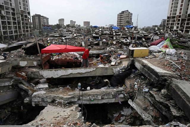 A person walks through the rubble of residential buildings that collapsed following the June 24 earthquakes, in Caraballeda, Venezuela, on July 20, 2026. (Photo by Federico PARRA / AFP)