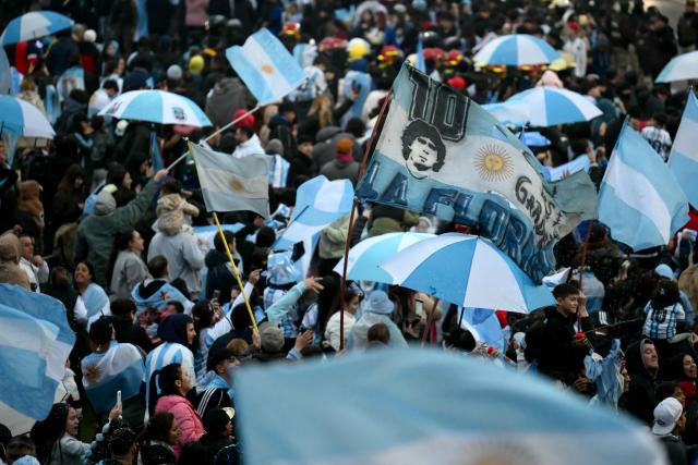 A fan waves a flag bearing an image of Argentine football legend Diego Maradona near the Argentine Football Association (AFA) training camp in Ezeiza, Buenos Aires Province, on July 20, 2026, while awaiting the arrival of Argentina's national football team from the United States following its defeat in the 2026 FIFA World Cup final. (Photo by Luis ROBAYO / AFP)