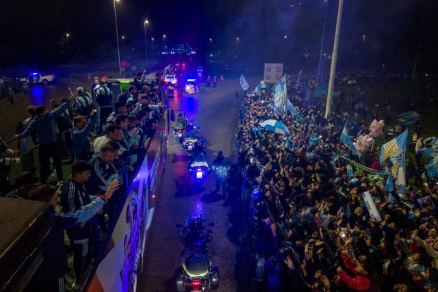 In this aerial view Argentina's national football team rides aboard an open-top bus as it arrives at the Argentine Football Association (AFA) training camp in Ezeiza, Buenos Aires Province, on July 20, 2026, after returning from the United States following its defeat in the 2026 FIFA World Cup final. (Photo by Tomas CUESTA / AFP)