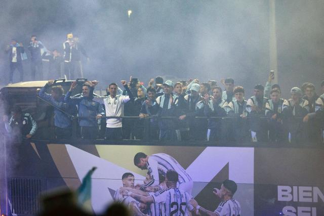 Argentina's head coach Lionel Scaloni (3-L) and members of Argentina's national football team wave aboard an open-top bus as they drive towards the Argentine Football Association (AFA) training camp in Ezeiza, Buenos Aires Province, on July 20, 2026, after returning from the United States following their defeat in the 2026 FIFA World Cup final. (Photo by TOMAS CUESTA / AFP)