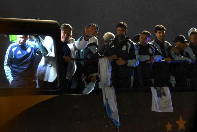 President of the Argentine Football Association Claudio Tapia (2-L) waves alongside members of Argentina's national football team aboard an open-top bus as they drive towards the Argentine Football Association (AFA) training camp in Ezeiza, Buenos Aires Province, on July 20, 2026, after returning from the United States following their defeat in the 2026 FIFA World Cup final. (Photo by Luis ROBAYO / AFP)
