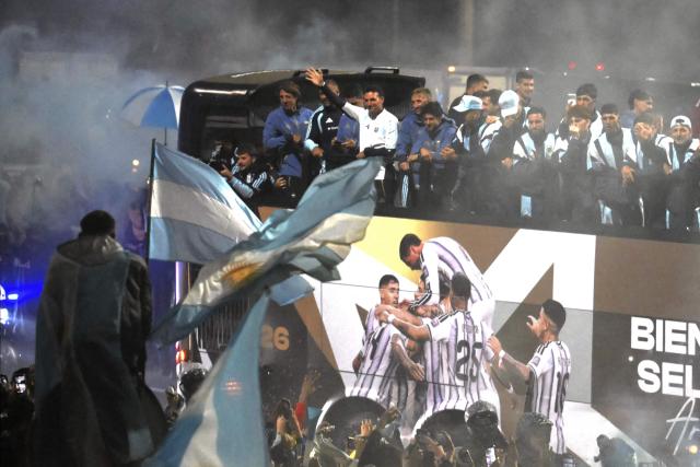 Argentina's head coach Lionel Scaloni (4-L) waves alongside members of Argentina's national football team aboard an open-top bus as they drive towards the Argentine Football Association (AFA) training camp in Ezeiza, Buenos Aires Province, on July 20, 2026, after returning from the United States following their defeat in the 2026 FIFA World Cup final. (Photo by Luis ROBAYO / AFP)