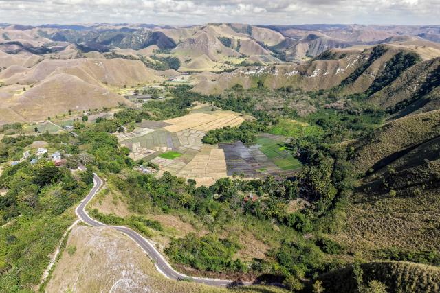 This photo taken on June 23, 2026 shows an aerial view of the landscape surrounding Tanggedu village in East Sumba, East Nusa Tenggara. Two hours from the tourist beaches of Bali, slavery is alive and well on the Indonesian island of Sumba, where people are still being born into bondage. Eight of out 10 of Sumba's population of 685,000 people are Christian but its older "marapu" belief system, that blends animism and ancestor worship, has deep roots. It divides society into three castes, "the nobles, called 'maramba' -- often large landowners -- ordinary people called 'kabihu' and the slaves/servants, the atas," said rights activist Martha Hebi, author of several studies on the subject. (Photo by BAY ISMOYO / AFP) / To go with Indonesia-Sumba-slavery, SPECIAL REPORT by Eric Bernaudeau