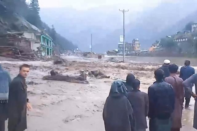 This frame grab from video footage recorded on July 20, 2026 shows people looking on beside a torrent of water at the scene of flooding in Afghanistan's Nuristan province. At least 20 people have been killed and more than 100 remain missing in flooding that hit Afghanistan's Nuristan province on July 20, officials said. (Photo by anonymous / AFP) / AFP is in direct contact with the source, who wishes to remain anonymous