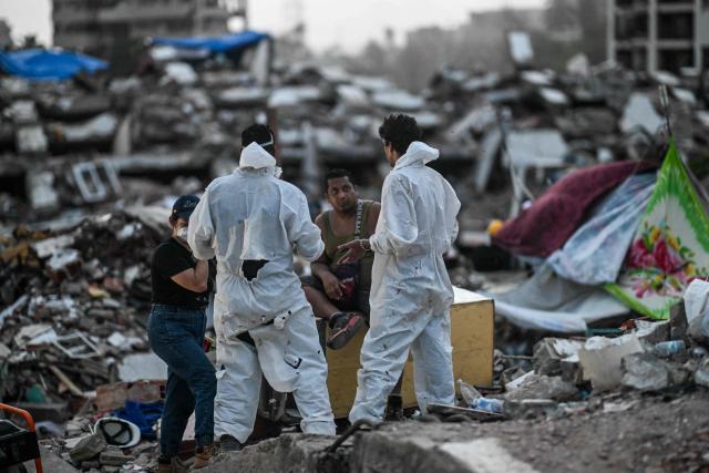 Forensic workers speak with relatives amid the rubble of a residential building that collapsed following the June 24 earthquakes, in Caraballeda, Venezuela, on July 20, 2026. The number of people killed in the powerful dual Venezuela earthquakes last month rose to 5,278, according to official figures updated Monday. The June 24 earthquakes, which recorded magnitudes of 7.2 and 7.5, profoundly impacted the north of the country, particularly the coastal state of La Guaira, near the capital Caracas. (Photo by Juan BARRETO / AFP)