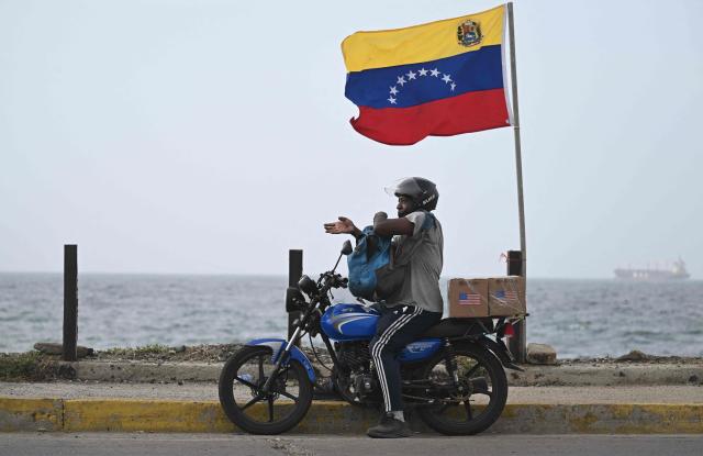 A motorcyclist carries two boxes of food delivered by the US Army following the June 24 earthquakes in Catia La Mar, Venezuela, on July 20, 2026. The number of people killed in the powerful dual Venezuela earthquakes last month rose to 5,278, according to official figures updated Monday. The June 24 earthquakes, which recorded magnitudes of 7.2 and 7.5, profoundly impacted the north of the country, particularly the coastal state of La Guaira, near the capital Caracas. (Photo by Juan BARRETO / AFP)