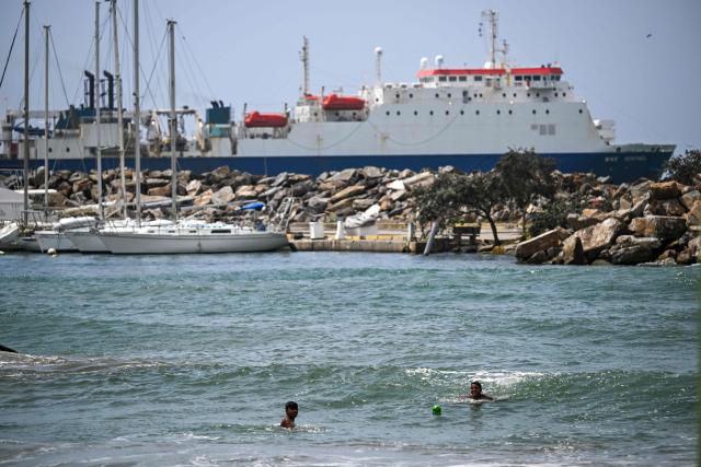 Two children swim at a beach in Catia La Mar, Venezuela, with a ship in the distance on July 20, 2026. (Photo by Juan BARRETO / AFP)