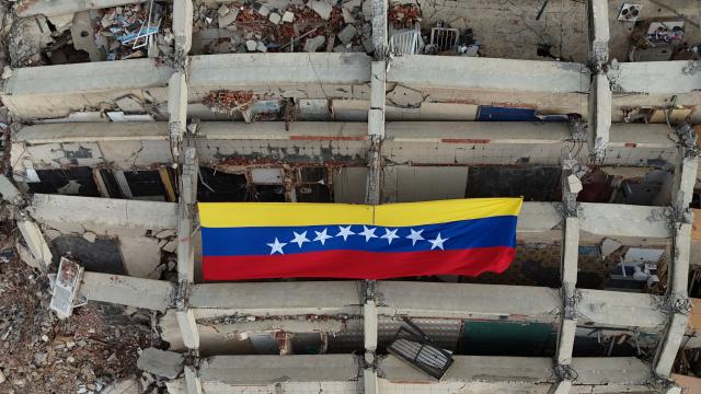 A large Venezuelan flag hangs from a residential building destroyed during the earthquakes of June 24, in Caraballeda, Venezuela, on July 20, 2026. The number of people killed in the powerful dual Venezuela earthquakes last month rose to 5,278, according to official figures updated Monday. The June 24 earthquakes, which recorded magnitudes of 7.2 and 7.5, profoundly impacted the north of the country, particularly the coastal state of La Guaira, near the capital Caracas. (Photo by Juan BARRETO / AFP)