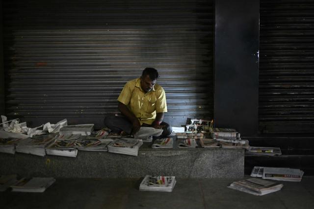 A vendor sorts newspapers along a road in Chennai on July 21, 2026. (Photo by R.Satish BABU / AFP)