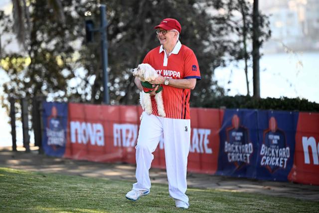 Australian Prime Minister Anthony Albanese holds his dog Toto during a charity backyard cricket match at Kirribilli House in Sydney on July 21, 2026. (Photo by DAN HIMBRECHTS / POOL / AFP)