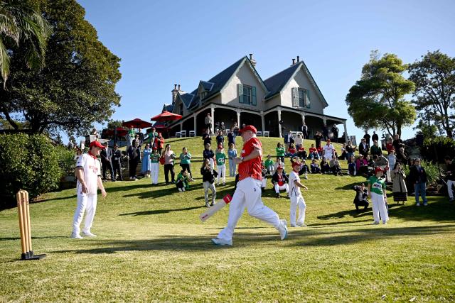 Australian Prime Minister Anthony Albanese (C) runs between the wickets as he takes part in a charity backyard cricket match at Kirribilli House in Sydney on July 21, 2026. (Photo by DAN HIMBRECHTS / POOL / AFP)