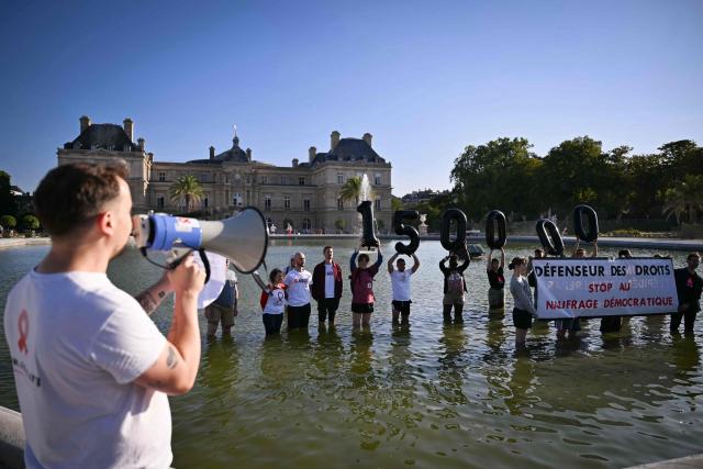 Protestors hold a banenr reading "Human Rights Defender: stop the democratic sinking", during a gathering organised by French association AIDES and Sidaction against the appointment of the new Human Rights Defender by senators at the Jardin du Luxembourg, in Paris on July 21, 2026. (Photo by Lou BENOIST / AFP)