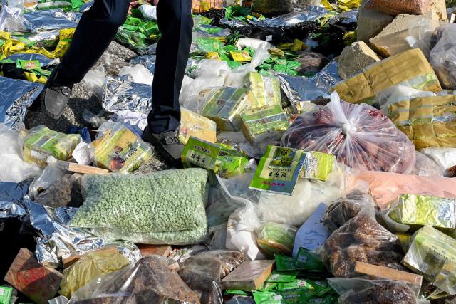 An official walks on seized drugs before they are burned during a destruction ceremony to mark the UN's "International Day against Drug Abuse and Illicit Trafficking" in Kandal province on July 21, 2026. (Photo by TANG CHHIN Sothy / AFP)