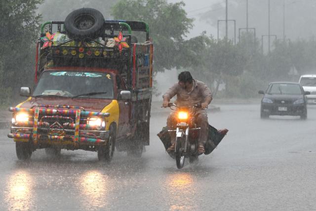 Commuters ride along a street as it rains in Peshawar, in Pakistan's Khyber Pakhtunkhwa province on July 21, 2026. (Photo by Abdul MAJEED / AFP)