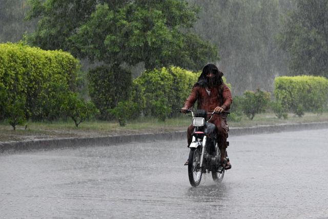 A commuter rides his motorbike along a street as it rains in Peshawar, in Pakistan's Khyber Pakhtunkhwa province on July 21, 2026. (Photo by Abdul MAJEED / AFP)