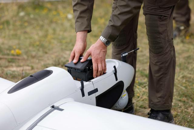 An employee of German manufacturer of civil and military surveillance drones Quantum Systems removes a battery from an unmanned Reliant reconnaissance drone after its flight on the military grounds near Hohenfels, Bavaria, southern Germany, during a press presentation of the system, on July 21, 2026. Reliant is an unmanned reconnaissance system for long-range ISR (Intelligence, Surveillance and Reconnaissance) missions – will be demonstrated to you under realistic operational conditions. (Photo by Michaela STACHE / AFP)