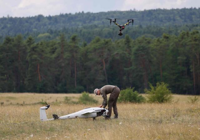 An employee of German manufacturer of civil and military surveillance drones Quantum Systems inspects an unmanned Reliant reconnaissance drone after its flight on the military grounds near Hohenfels, Bavaria, southern Germany, during a press presentation of the system, on July 21, 2026. Reliant is an unmanned reconnaissance system for long-range ISR (Intelligence, Surveillance and Reconnaissance) missions – will be demonstrated to you under realistic operational conditions. (Photo by Michaela STACHE / AFP)