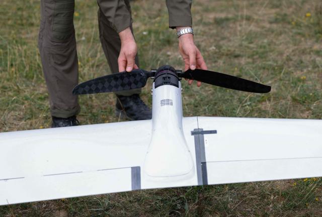 An employee of German manufacturer of civil and military surveillance drones Quantum Systems inspects the propeller of an unmanned Reliant reconnaissance drone after its flight on the military grounds near Hohenfels, Bavaria, southern Germany, during a press presentation of the system, on July 21, 2026. Reliant is an unmanned reconnaissance system for long-range ISR (Intelligence, Surveillance and Reconnaissance) missions – will be demonstrated to you under realistic operational conditions. (Photo by Michaela STACHE / AFP)