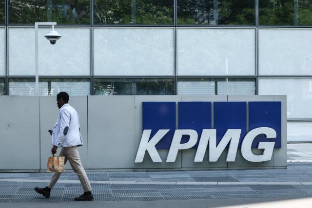 A man walks past the logo of KPMG, a global accounting, tax and consulting firm, at La Defense business district in Paris on July 21, 2026.  (Photo by Xavier GALIANA / AFP)