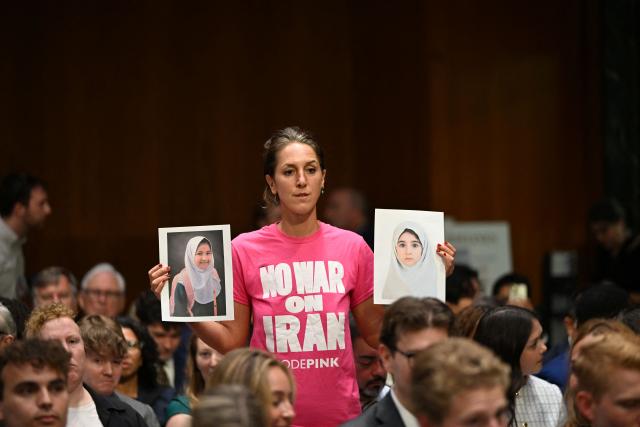 A protester against the war in Iran holds pictures before US Defense Secretary Pete Hegseth, Chairman of the Joint Chiefs of Staff Gen. Dan Caine and Secretary of Agriculture Brooke Rollins are to testify during a Senate Committee on Appropriations hearing on Capitol Hill in Washington, DC on July 21, 2026. US lawmakers are conducting a hearing to examine a review of US President Donald Trump's supplemental funding request of June 24, 2026. (Photo by Alex WROBLEWSKI / AFP)
