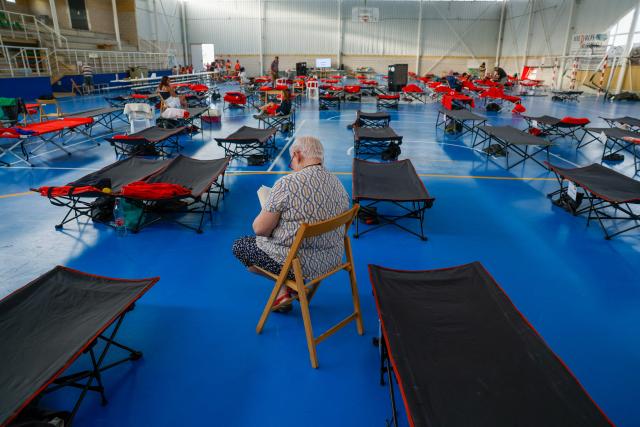 An evacuated resident passes the time reading at a sportshall during a huge wildfire  that has devastated 29,000 hectares in the Guadalajar province,  in Humanes, north of Madrid on July 21, 2026. (Photo by Pierre-Philippe MARCOU / AFP)