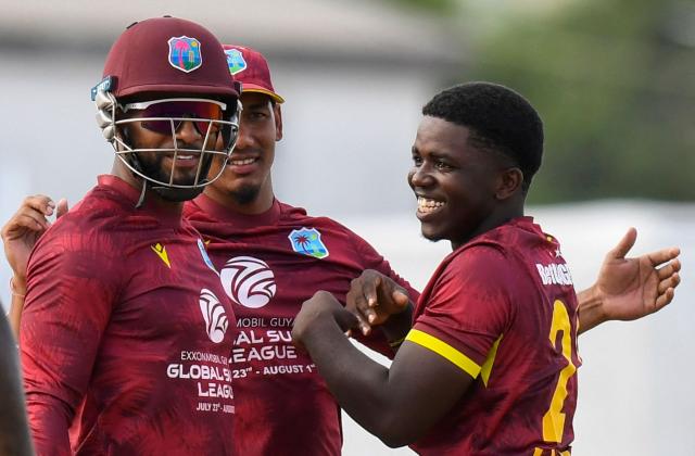 Bowler Vitel Lawes of West Indies (R) is congratulated by teammates, wicketkeeper/captain Shai Hope (L) and Gudakesh Motie, after taking the wicket of opening batsman Will Young of New Zealand during the fifth and final one day international (ODI) cricket match between West Indies and New Zealand at Kensington Oval in Bridgetown, Barbados on July 21, 2026. (Photo by Randy Brooks / AFP)