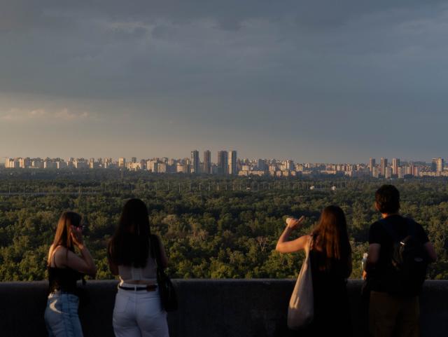 People look over the city from an observation platform in the Podil district after a rain shower, in Kyiv on July 21, 2026, amid the Russian invasion of Ukraine. (Photo by Tetiana DZHAFAROVA / AFP)