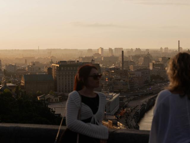 People look over the city from an observation platform in the Podil district after a rain shower, in Kyiv on July 21, 2026, amid the Russian invasion of Ukraine. (Photo by Tetiana DZHAFAROVA / AFP)