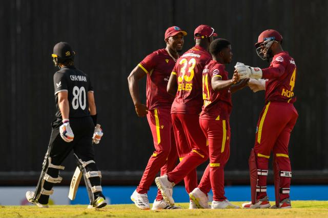 Batsman Mark Chapman of New Zealand (L) walks off the pitch after his dismissal by bowler Vitel Lawes of West Indies (2nd-R), who celebrates with teammates Shai Hope (R), Jayden Seales (C) and Matthew Forde during the fifth and final one day international (ODI) cricket match between West Indies and New Zealand at Kensington Oval in Bridgetown, Barbados on July 21, 2026. (Photo by Randy Brooks / AFP)